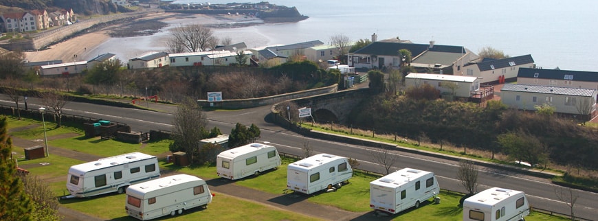 A group of rvs parked on a hill overlooking the sea, offering a serene and picturesque view for tourists seeking a Brexit-free retreat with exceptional hospitality.