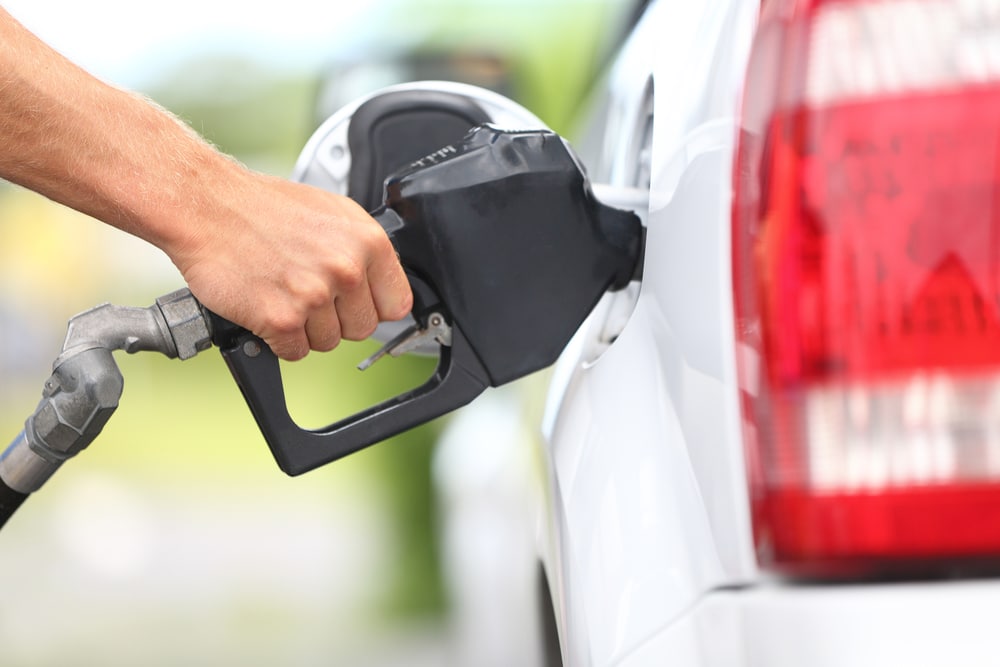 A person filling up a car with gas during the month with the smallest increase in gas prices.