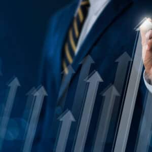 A businessman holding a marker in front of a graph with upward arrows, showcasing positive Comp-Sales growth.