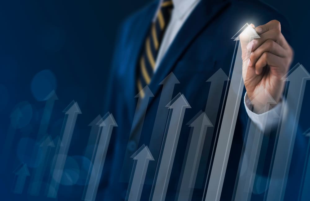 A businessman holding a marker in front of a graph with upward arrows, showcasing positive Comp-Sales growth.