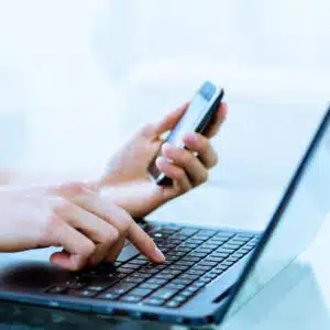 Victor Vesnaver, the Chief Operating Officer of RMS North America, diligently types on his laptop while simultaneously checking messages on his cell phone.