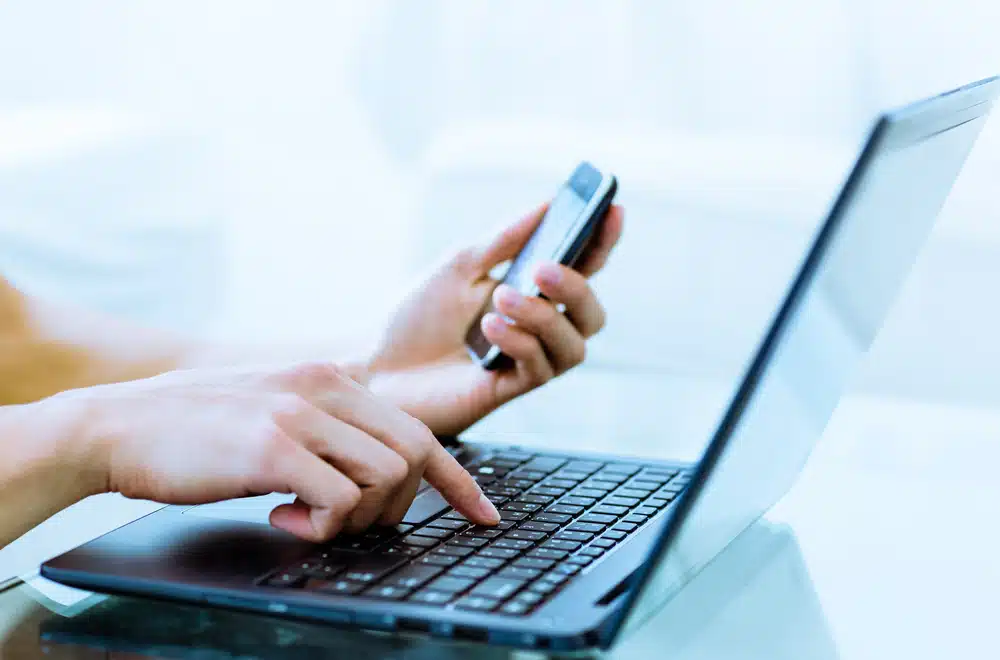 Victor Vesnaver, the Chief Operating Officer of RMS North America, diligently types on his laptop while simultaneously checking messages on his cell phone.