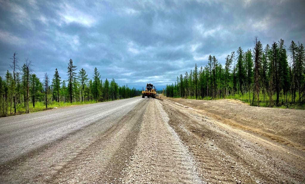 A bulldozer is driving down the Tłı̨chǫ Highway.