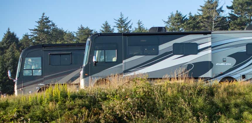 Two Thor Industries RVs parked on a grassy hillside.