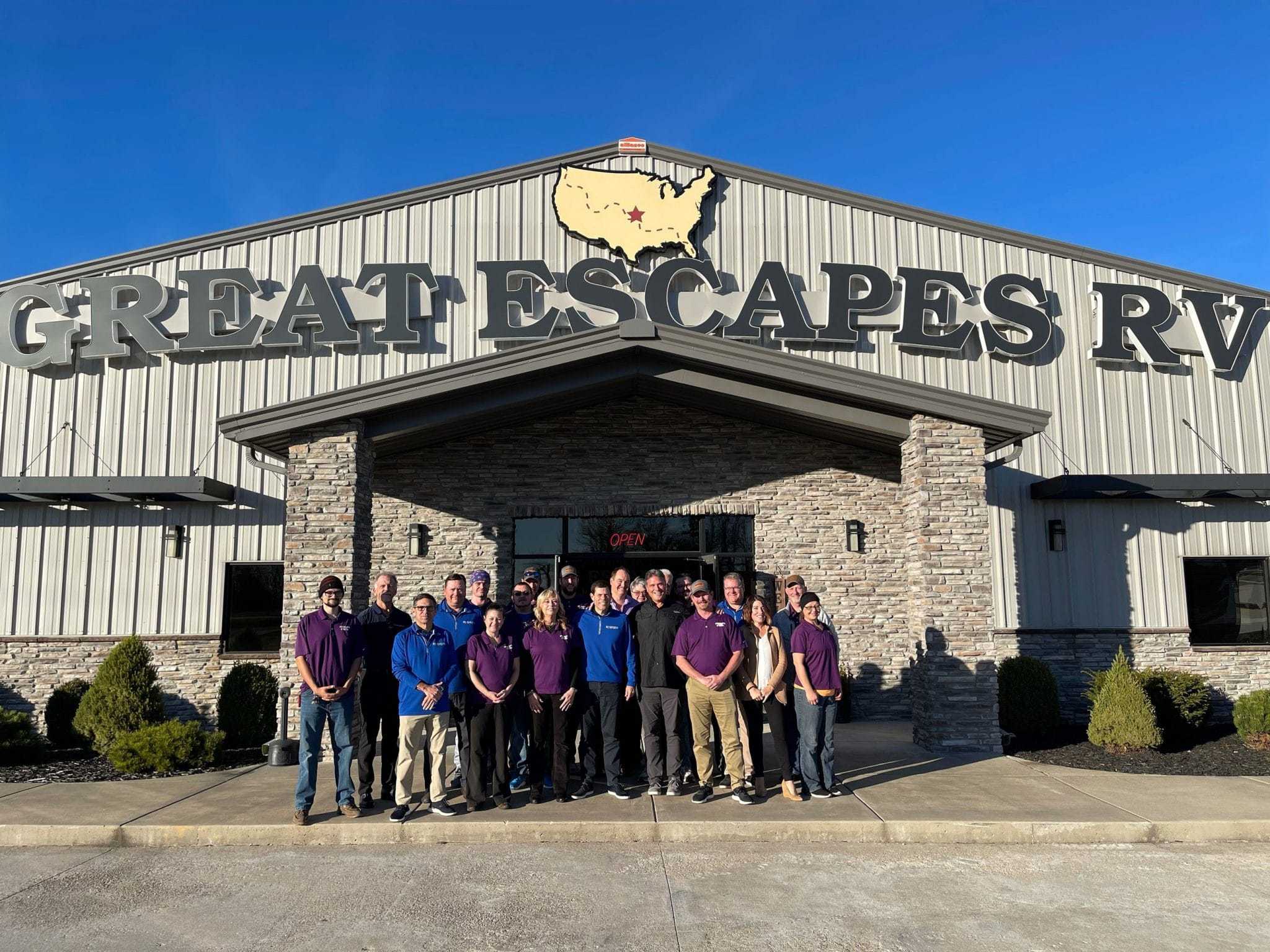 A group of people standing in front of a Great Escapes RV, purchased from an RV Retailer.