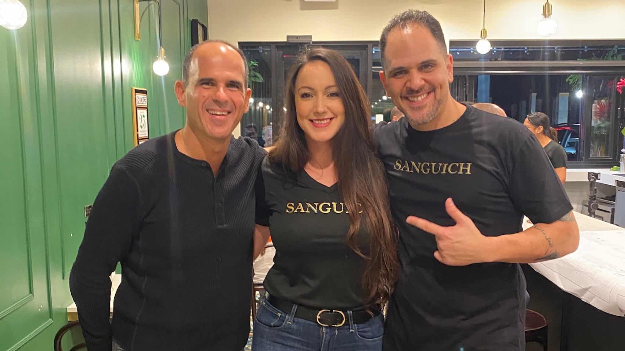 Marcus Lemonis, Sanguich, and partner posing for a picture in a restaurant.