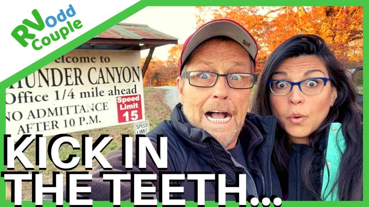 Two people standing in front of a sign at a campground.