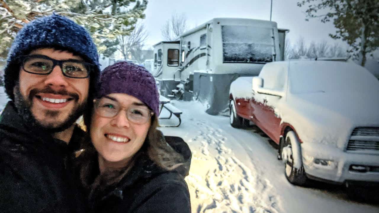 A couple posing for a selfie in front of their winterized RV setup.