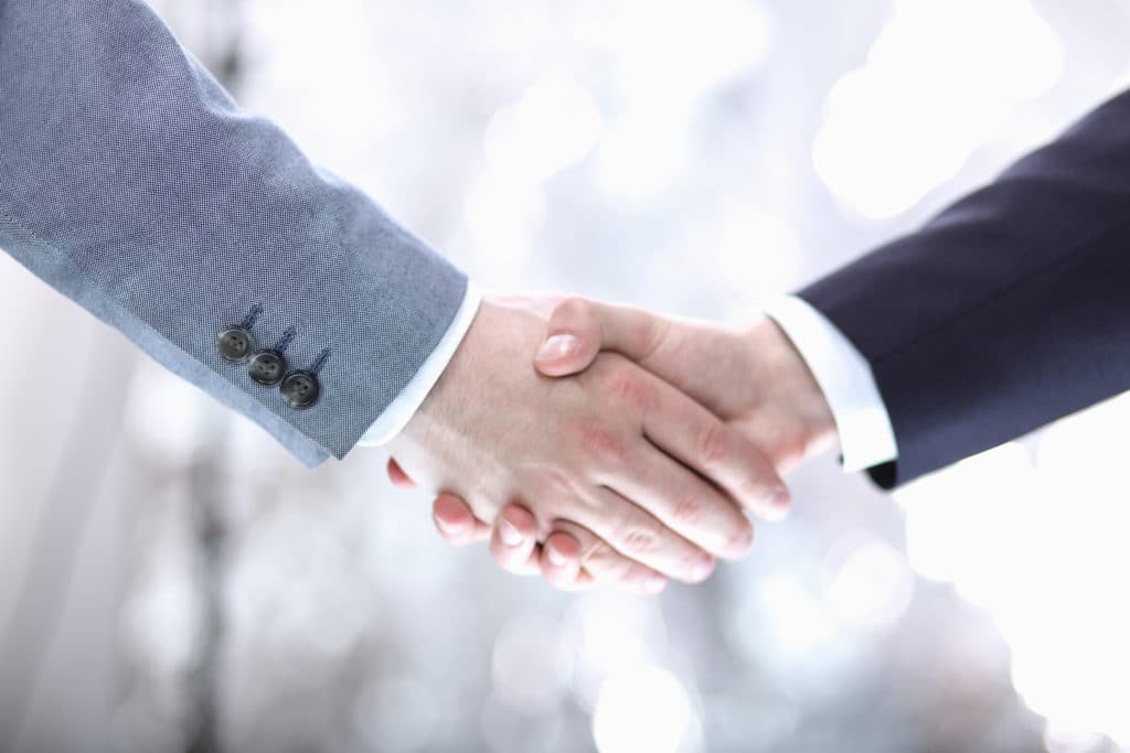 Two businessmen shaking hands in front of a blurred background at Summerhill Resorts
