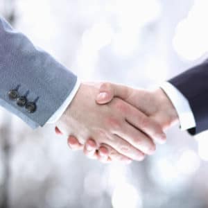 Two businessmen shaking hands in front of a blurred background at Summerhill Resorts