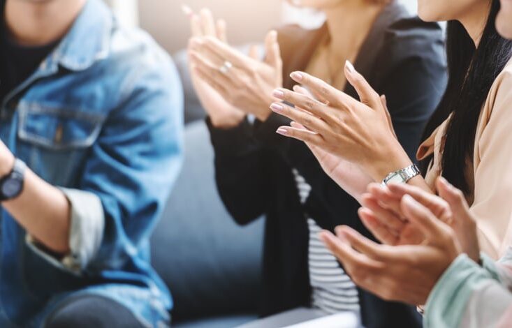 A group of people clapping together at the National Campground Association.