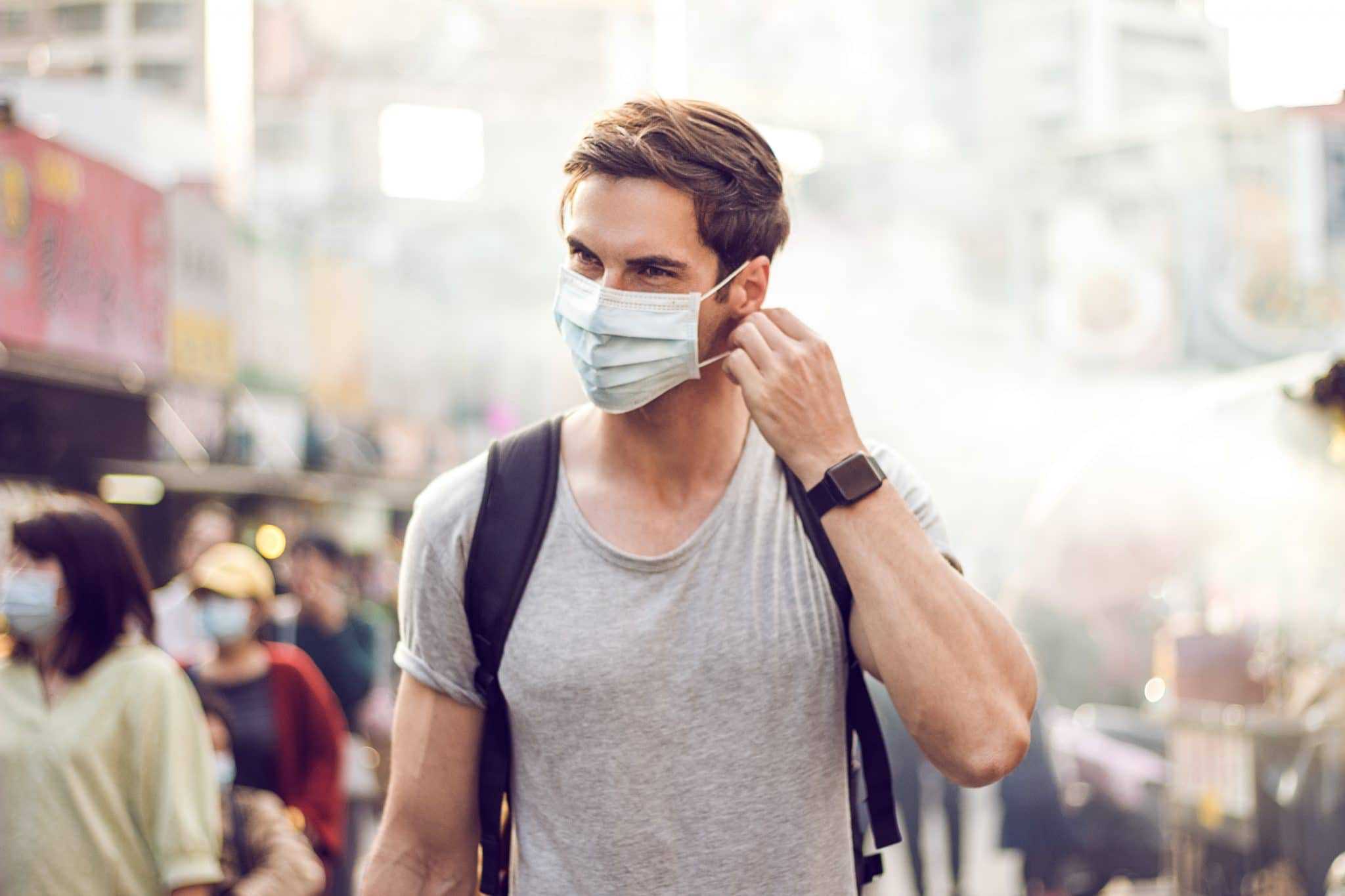 A man wearing a face mask amidst Facility Access Restriction in a crowded Northland street.