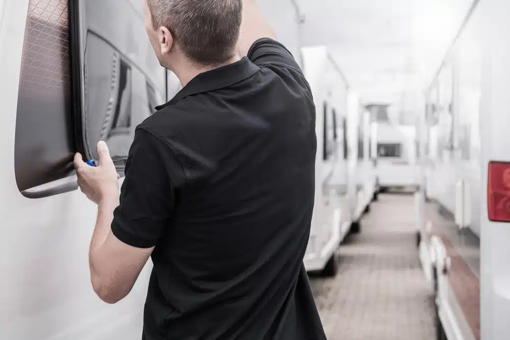 A man is repairing a window on an rv.