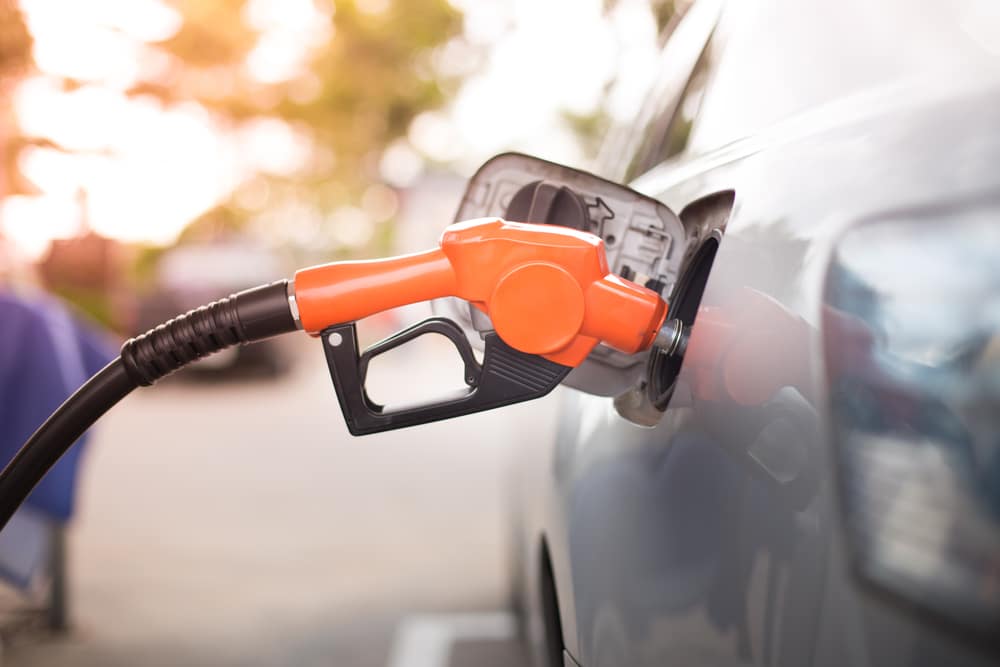 Gas Prices drop during COVID-19 resurgence as gas pump fills car.