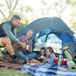 A family is having a picnic near their tent at a holiday camp.