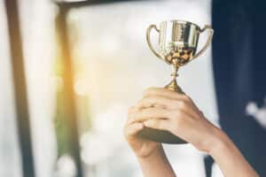 A woman holding up a trophy in front of a window.