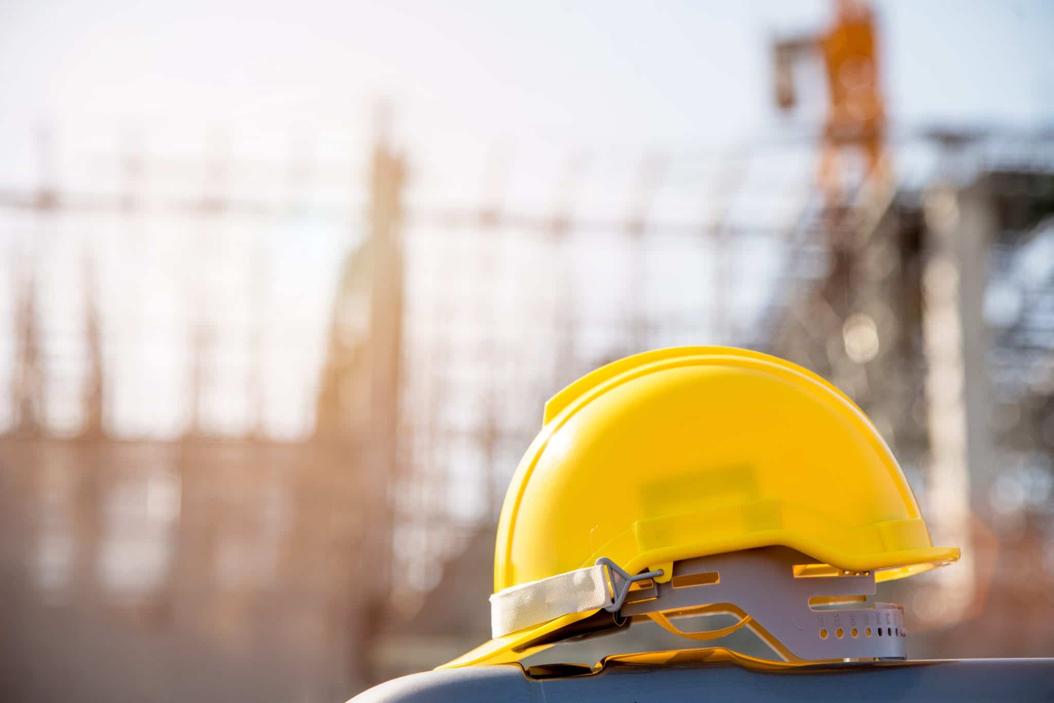 A yellow hard hat sits on top of a construction site.