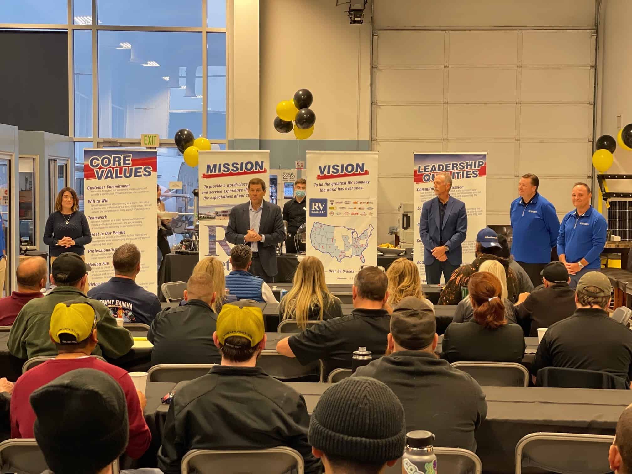 A group of RV Retailer representatives standing in front of a room full of people during their expansion into the Pacific Northwest.