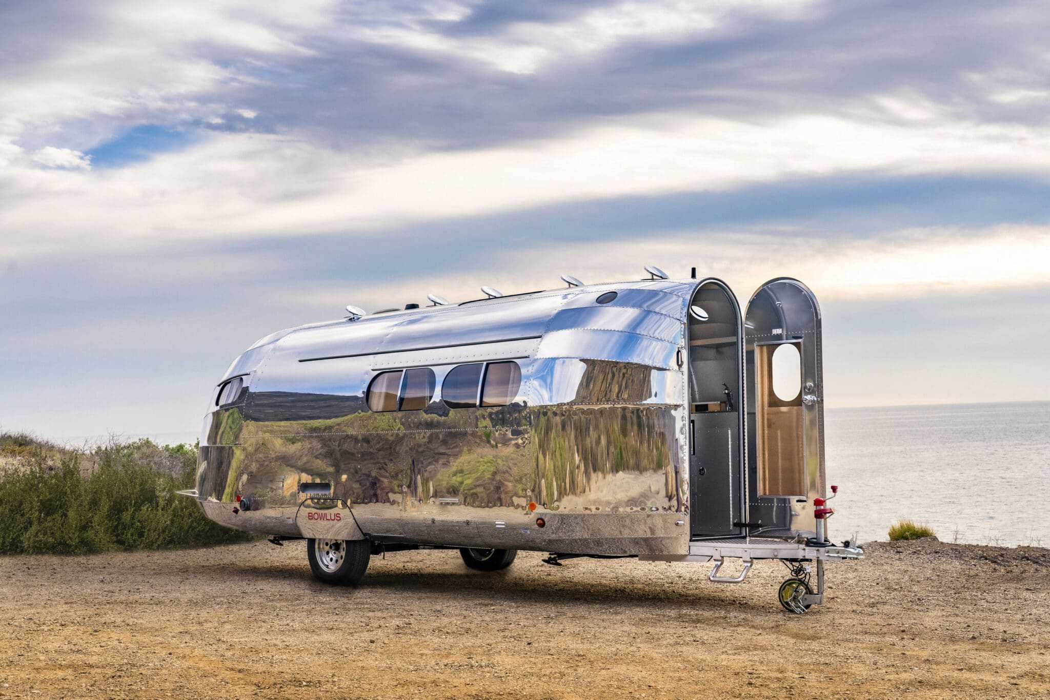 A Bowlus airstream trailer parked near the ocean.