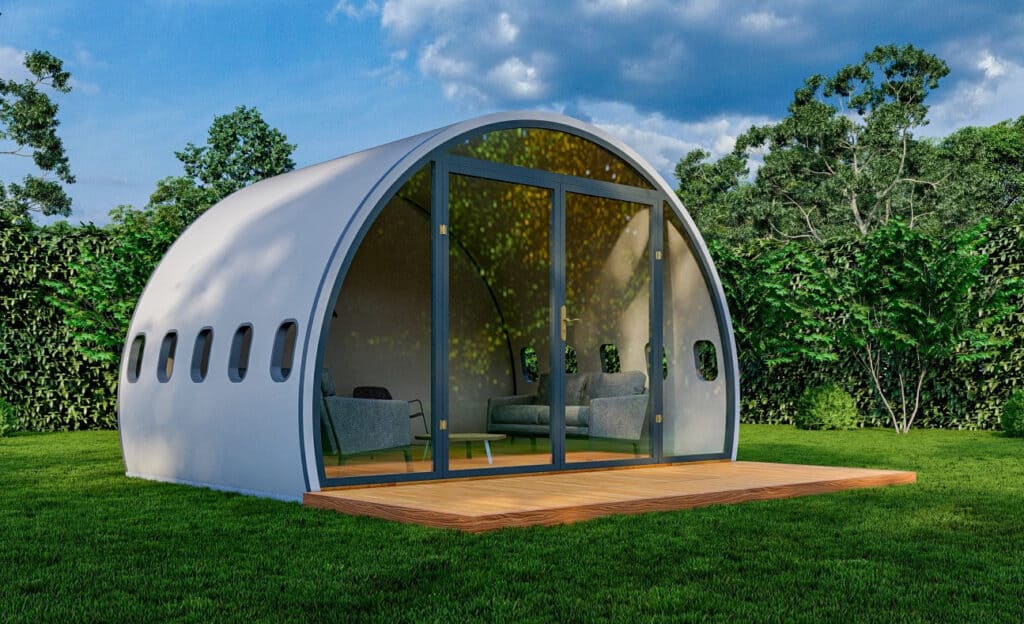 An upcycled airplane-shaped house nestled in a grassy area.