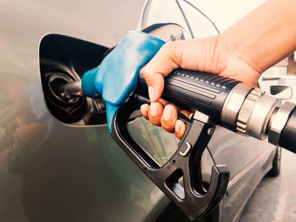 A person is filling up a car with gas, oblivious to the fluctuating pump prices.