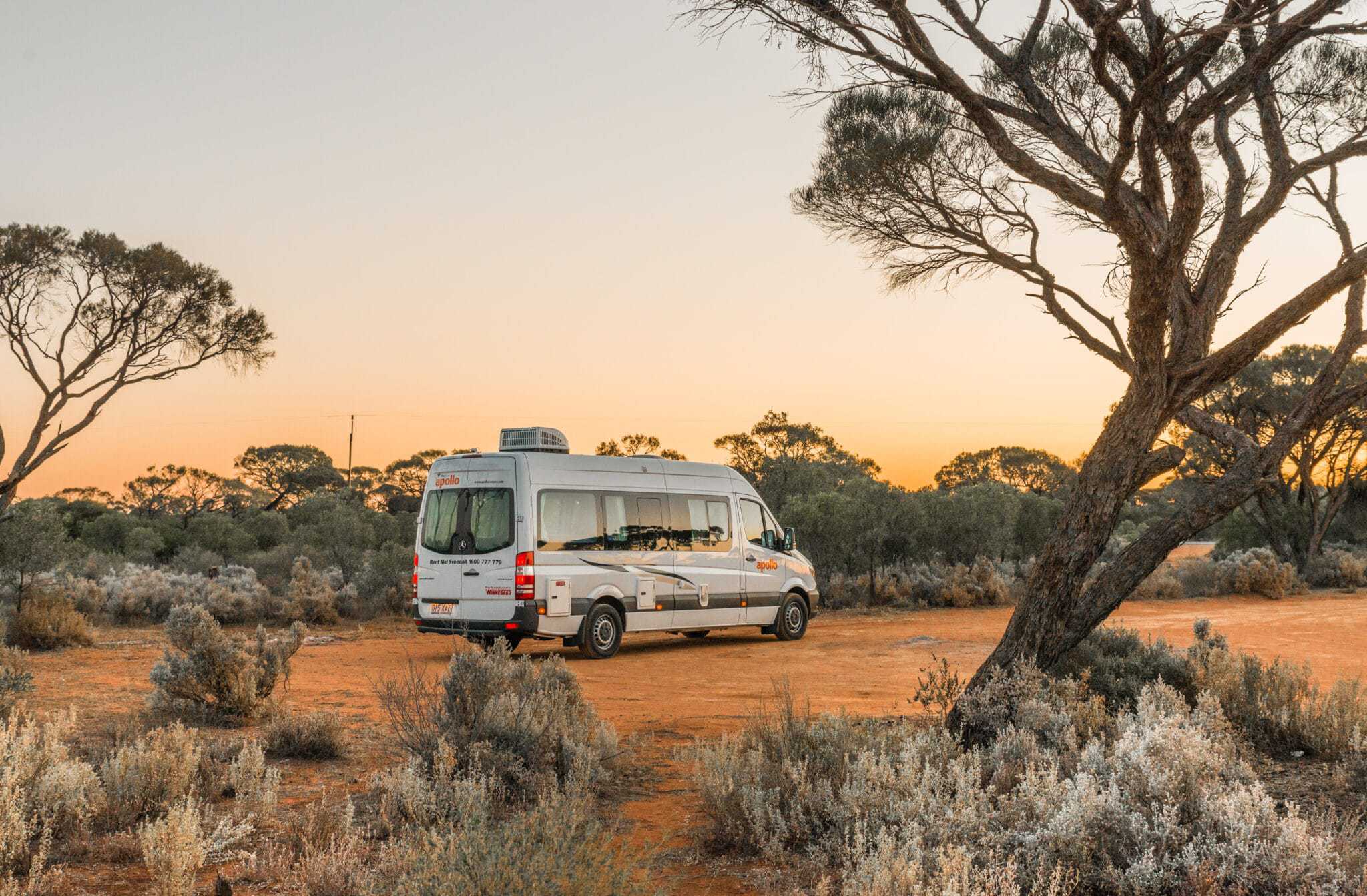 An Australian RV parked in the desert at sunset, showcasing its unique flourishes.