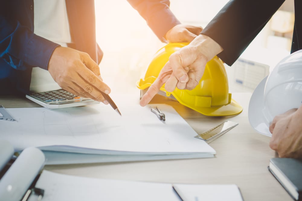 Two people working on a project with a hard hat on their heads.