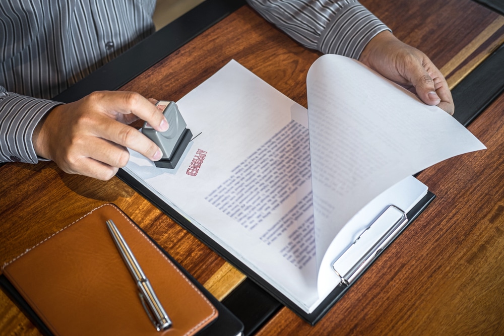 A man is signing a document with a rubber stamp.