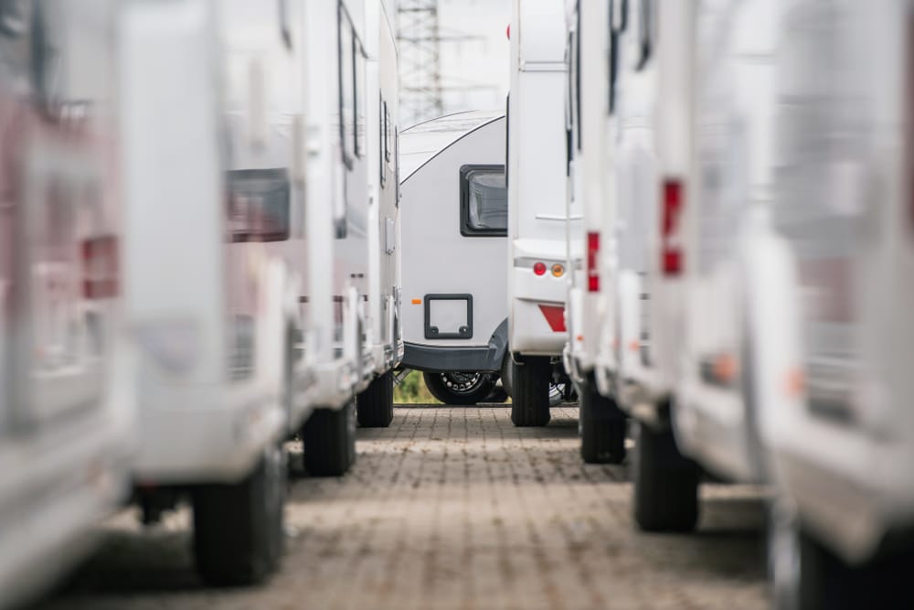 A row of rvs parked in a parking lot, certified by the Society of Certified RV Professionals.