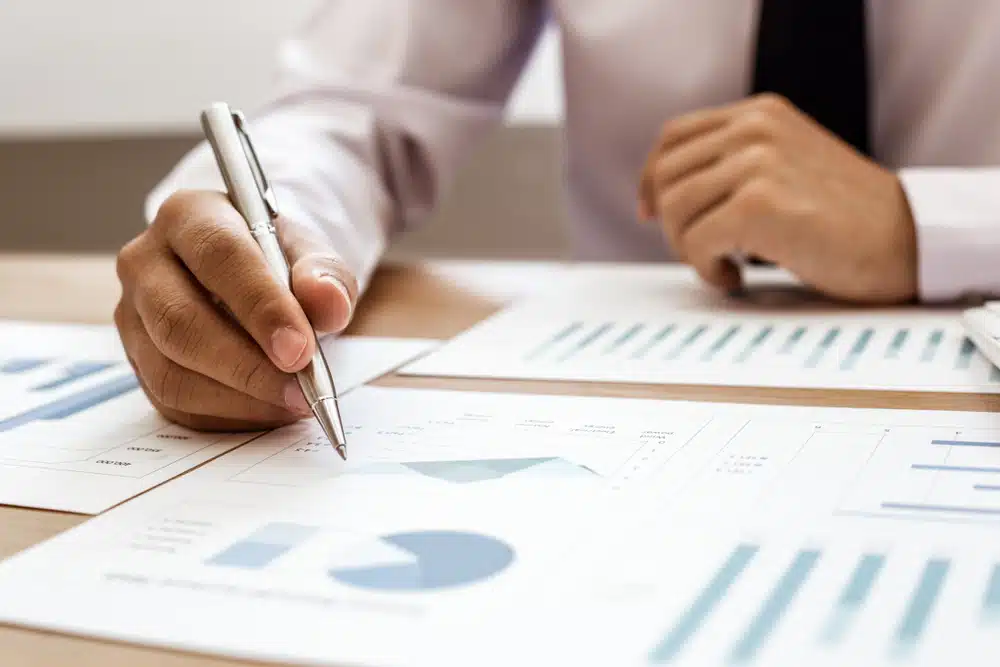 A businessman from Ocean Bio-Chem, a leading company specializing in marine products, is seen diligently writing on a piece of paper covered in graphs. This seems like an exciting moment as the company's record