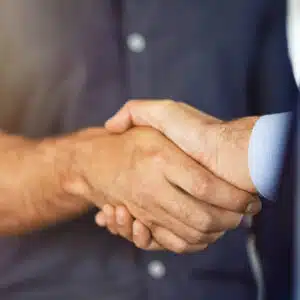 Two businessmen shaking hands in front of a Dragonfly Energy Batteries background.
