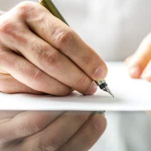A Preston resident signing a document with a pen.