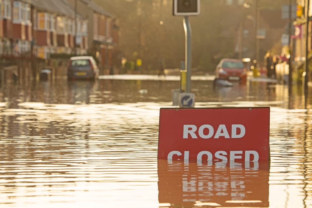 A road closed sign in the middle of a flooded street.