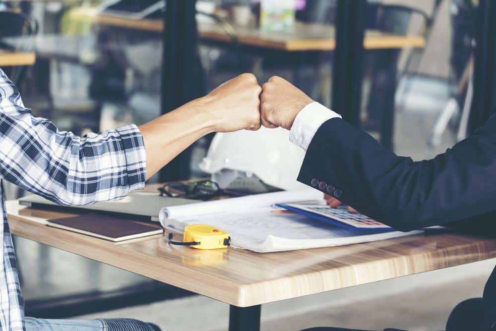 Two businessmen shaking hands at a table, displaying partnership in AquaHot.