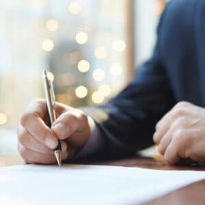 A businessman signing a purchase agreement document with a pen.