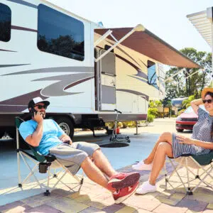 Two people sitting in chairs in front of an RV at an Australian caravan park.