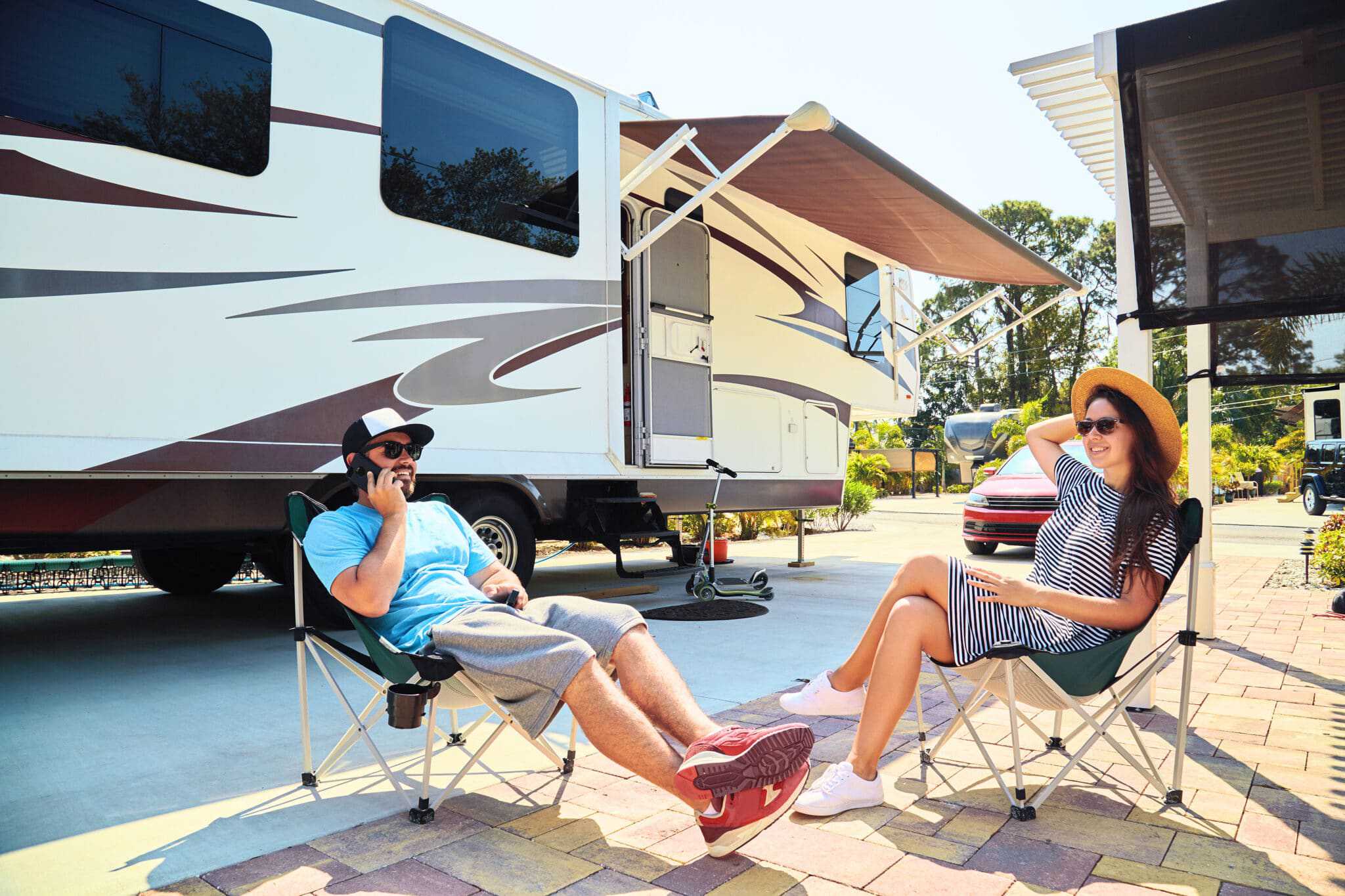 Two people sitting in chairs in front of an RV at an Australian caravan park.