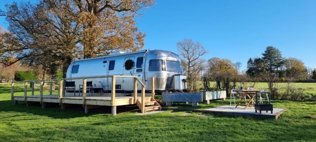 An American-style caravan sits on a wooden deck in a UK farm field.