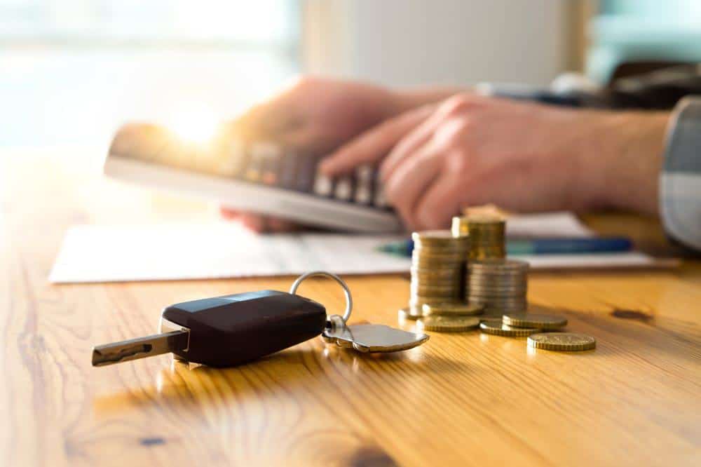 A man is holding a car key on a table.