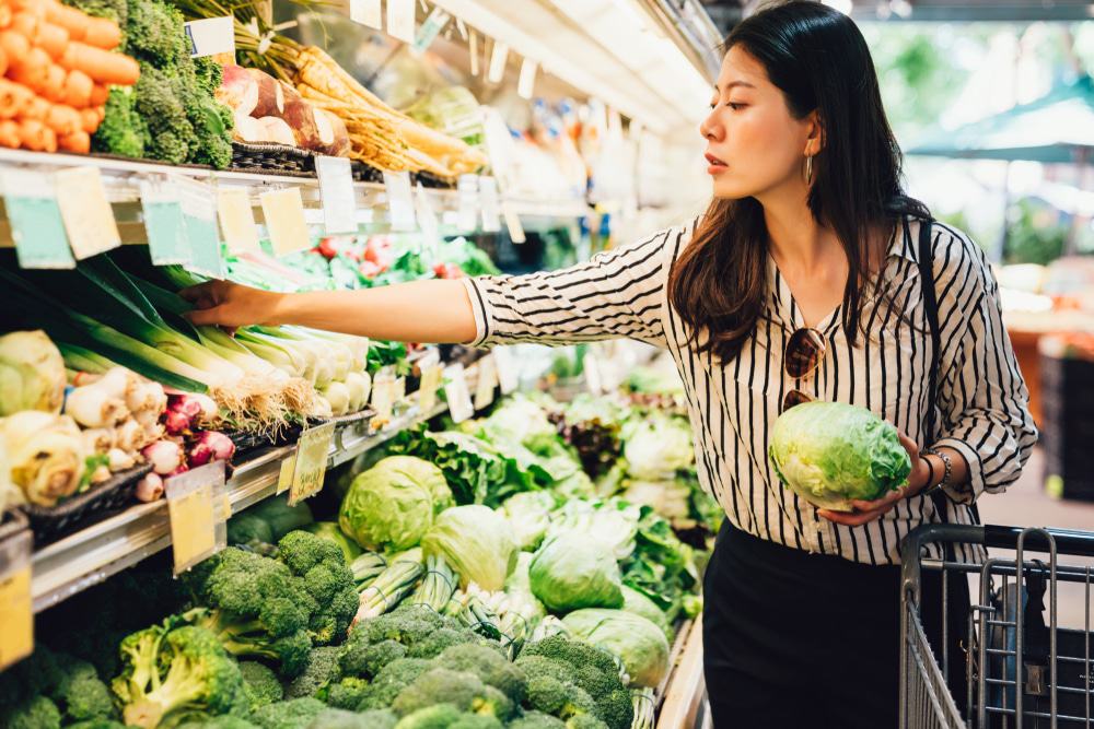 In January, a woman is choosing vegetables in a grocery store as consumer confidence has weakened.