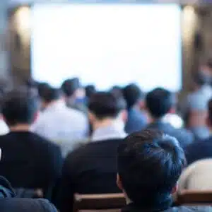 A group of people at the CampCalNOW Summit in an auditorium, watching a presentation on Park Rules by Rudderow Law Group.
