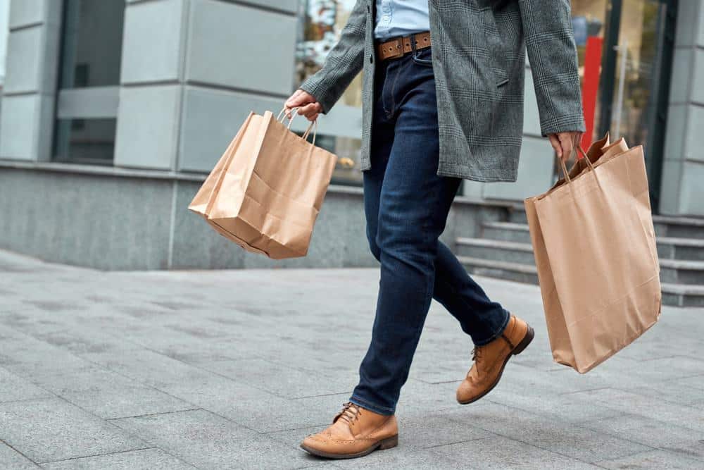 A man with shopping bags walking down the street, showcasing consumer confidence.