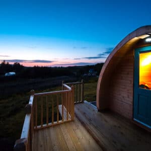 A wooden cabin sitting on a deck at dusk.
