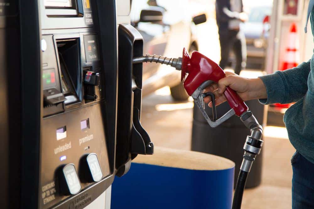 A man filling up his car with gas at a gas station amidst March's higher gas prices, with no signs of slowing.