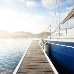 A blue and white sailboat docks at a marina.