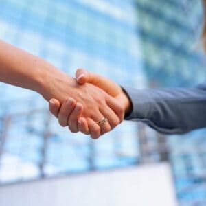 Two business people shaking hands in front of a building.