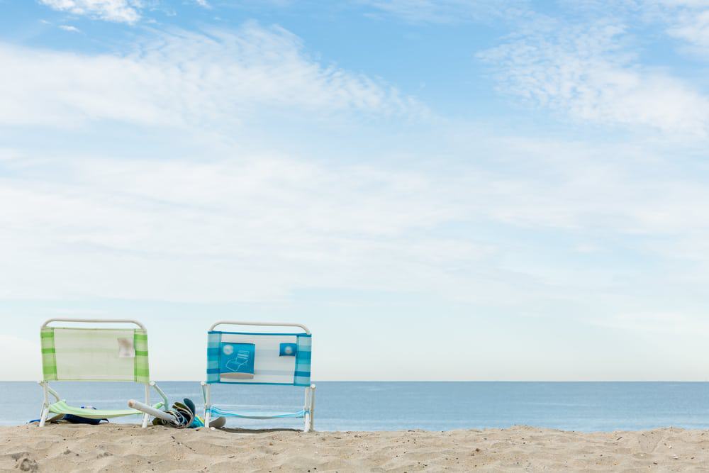 Two beach chairs sit on the sandy shore at the Bolivar Beach Club, open to RV Resort guests and offering stunning ocean views.