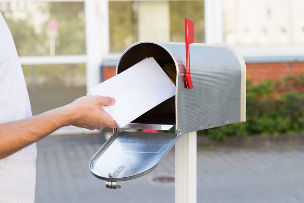 A man is putting a letter into a mailbox at Prospect Lake Campground.