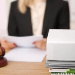 A woman named Leland sits at a desk, surrounded by papers and holds a gavel. She is working on amending the zoning ordinance for RV Parks.