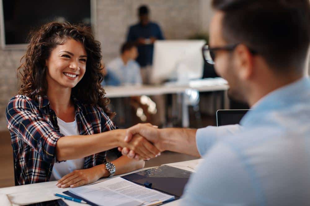 A woman shaking hands with a man in a U.S. office.